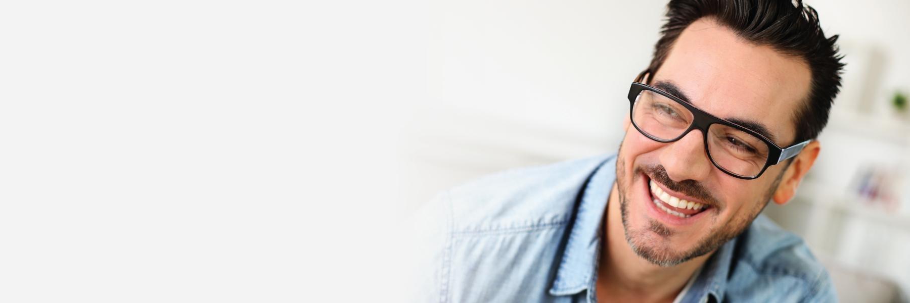 man with black glasses smiling after getting dental implants