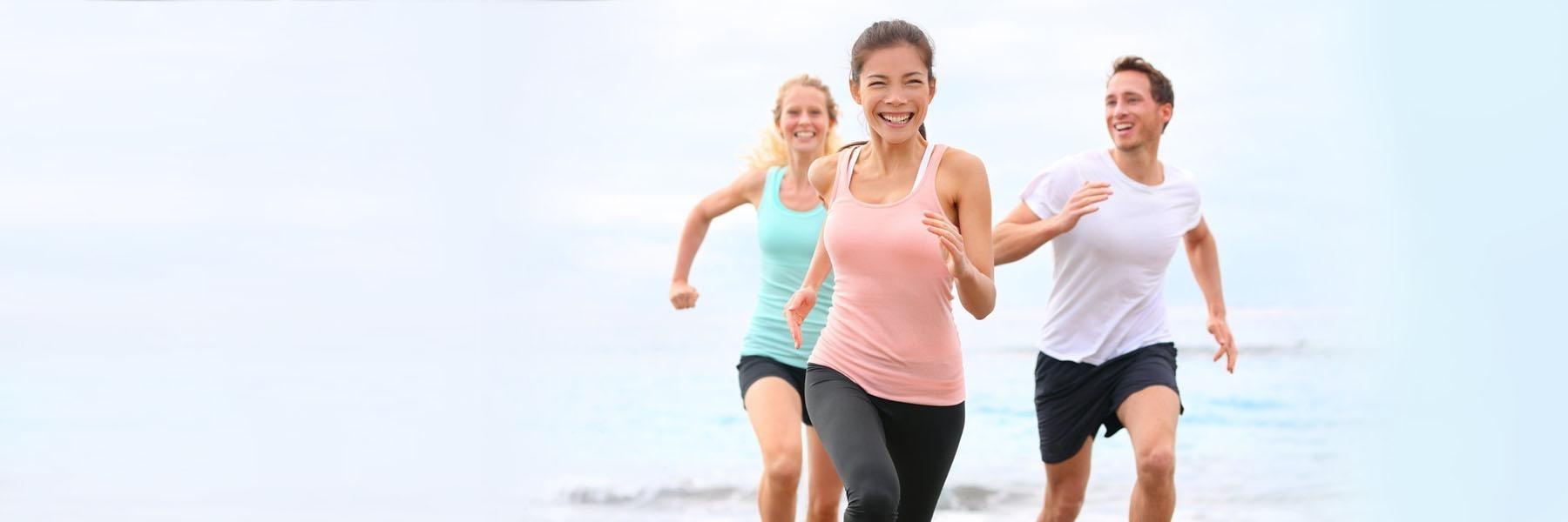 two woman and man jogging on beach