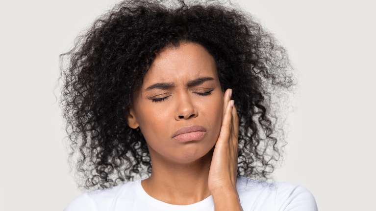 A lady holding her jaw due to TMJ Dysfunction in West Allis, WI.